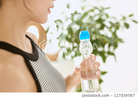 Smiling young woman enjoying summer refreshing drink in room Smiling young woman enjoying summer refreshing drink in room 127830567