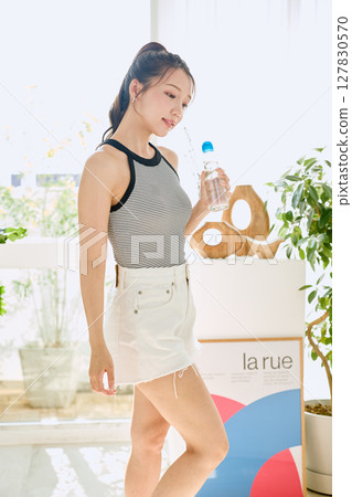 微笑的年輕女士在房間裡享用夏日清涼飲料 127830570