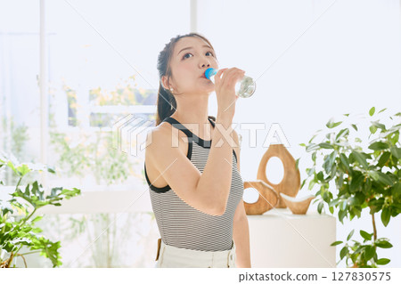 微笑的年輕女士在房間裡享用夏日清涼飲料 127830575