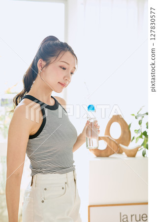 微笑的年輕女士在房間裡享用夏日清涼飲料 127830577