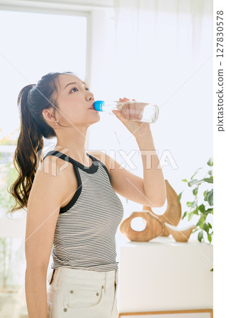 微笑的年輕女士在房間裡享用夏日清涼飲料 127830578