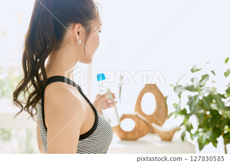 Smiling young woman enjoying summer refreshing drink in room 127830585