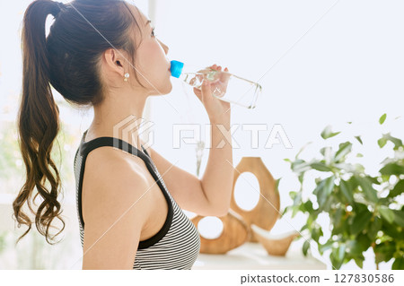 微笑的年輕女士在房間裡享用夏日清涼飲料 127830586