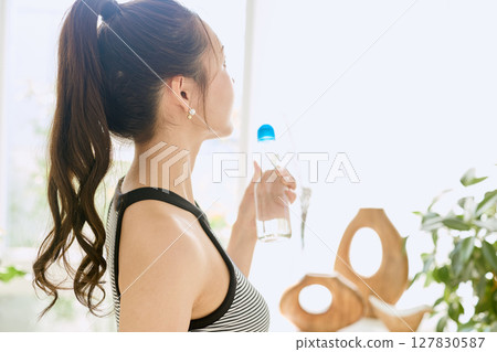微笑的年輕女士在房間裡享用夏日清涼飲料 127830587