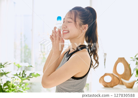 微笑的年輕女士在房間裡享用夏日清涼飲料 127830588