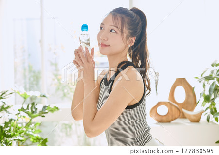 微笑的年輕女士在房間裡享用夏日清涼飲料 127830595