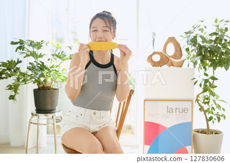 房間裡,微笑的年輕女子手裡拿著玉米 房間裡,微笑的年輕女子手裡拿著玉米 127830606