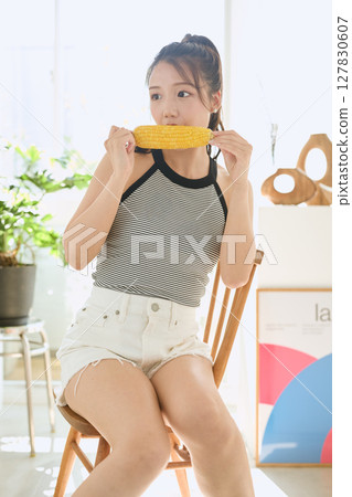 房間裡,微笑的年輕女子手裡拿著玉米 房間裡,微笑的年輕女子手裡拿著玉米 127830607