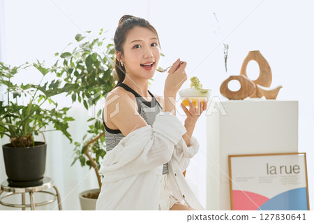 一位微笑的年輕女子吃刨冰享受夏日的生活方式 127830641