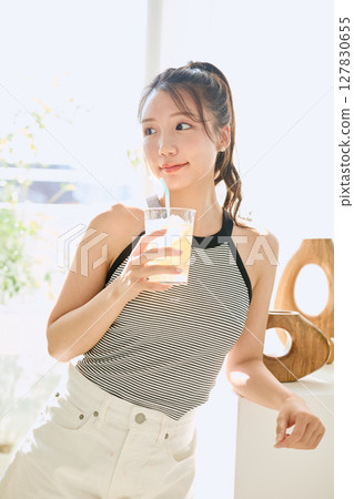 Summer refreshing young woman drinking lemonade in room 127830655