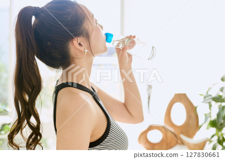 微笑的年輕女士在房間裡享用夏日清涼飲料 微笑的年輕女士在房間裡享用夏日清涼飲料 127830661