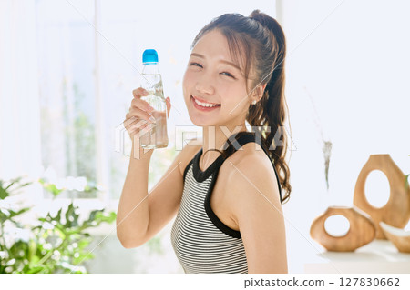 微笑的年輕女士在房間裡享用夏日清涼飲料 127830662
