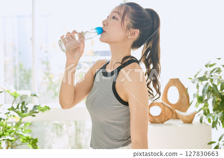 Smiling young woman enjoying summer refreshing drink in room 127830663