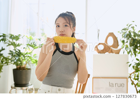 房間裡，微笑的年輕女子手裡拿著玉米 127830673
