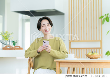 Middle-aged housewife using a smartphone at home Middle-aged housewife using a smartphone at home 127831019