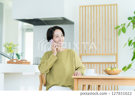 Middle-aged housewife making a phone call at home Middle-aged housewife making a phone call at home 127831022