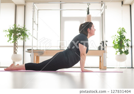 A plump woman does Pilates in a studio. A plump woman does Pilates in a studio. 127831404