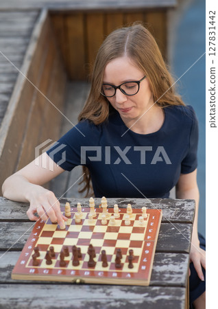 Caucasian woman playing chess outdoors.  127831442