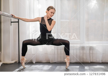 A beautiful Asian woman is dancing at the barre. Ballet dancer. 127831496