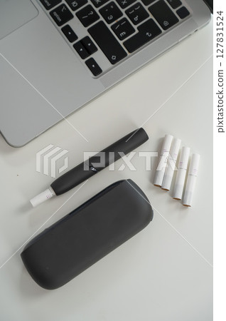 Tobacco heating system next to a laptop. Tobacco heating system next to a laptop. 127831524