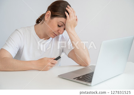 Tired woman smoking an electronic cigarette while working on a laptop. Tobacco heating system. Tired woman smoking an electronic cigarette while working on a laptop. Tobacco heating system. 127831525