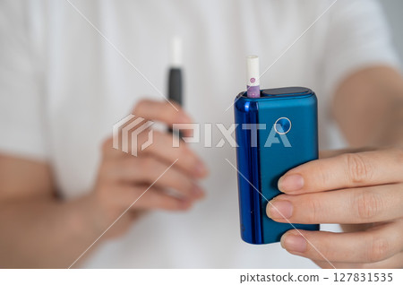 A woman compares two different tobacco heating systems. Electronic cigarette. 127831535