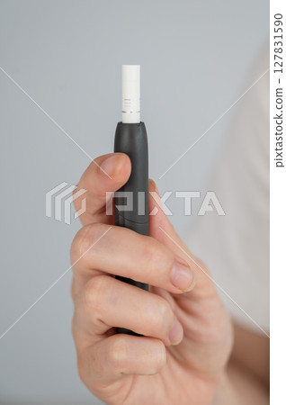 Faceless woman holding tobacco heating system. Faceless woman holding tobacco heating system. 127831590