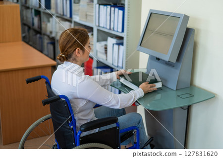 A woman in a wheelchair in the library. Special electronic catalog.  127831620
