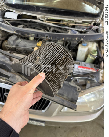 A dirty cabin air filter is replaced in a car. A dirty cabin air filter is replaced in a car. 127831642