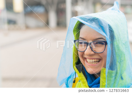 Portrait of a smiling woman with glasses wearing a raincoat outdoors. Portrait of a smiling woman with glasses wearing a raincoat outdoors. 127831663