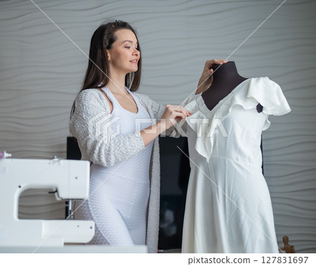 Caucasian woman sews a dress at home. Workspace of a seamstress 127831697
