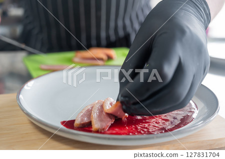The chef places the duck on cranberry sauce.  127831704