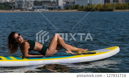 Caucasian woman posing on a SUP board. Summer sport. Caucasian woman posing on a SUP board. Summer sport. 127831718