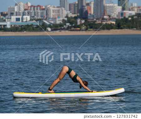 Caucasian woman doing yoga on a SUP board. Caucasian woman doing yoga on a SUP board. 127831742