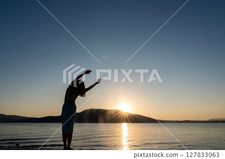 Silhouette of woman doing yoga and meditation exercises. 127833063