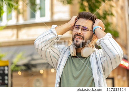 Sad unhappy young man thinks over life concerns, suffers from unfair situation on urban city street 127833124