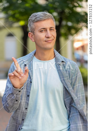 Upset man reacting to unpleasant awful idea, wave hand, shake head No while standing on city street 127833152
