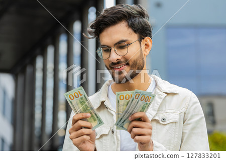 Happy successful rich Indian man counting money cash dollars salary profit reward bribe jackpot Happy successful rich Indian man counting money cash dollars salary profit reward bribe jackpot 127833201