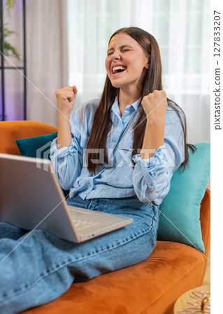 Surprised happy young woman using laptop computer, receive good news email message at home room Surprised happy young woman using laptop computer, receive good news email message at home room 127833207