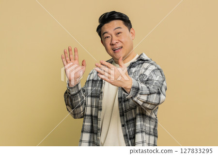 Happy man smiling friendly waving hands gesturing hello greeting or goodbye, meeting invitation Happy man smiling friendly waving hands gesturing hello greeting or goodbye, meeting invitation 127833295