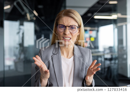 Video call, upset and disappointed woman looking into webcam, talking to colleagues and partners dissatisfied sitting inside office, online business meeting conference. Video call, upset and disappointed woman looking into webcam, talking to colleagues and partners dissatisfied sitting inside office, online business meeting conference. 127833416