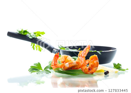Golden fried shrimps with spices and fresh lemon in a frying pan isolated on white Golden fried shrimps with spices and fresh lemon in a frying pan isolated on white 127833445