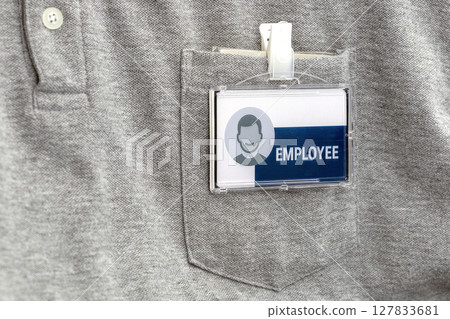 Gray shirt with employee badge clipped to pocket, featuring generic icon and word EMPLOYEE prominently displayed. badge is clear and professional 127833681
