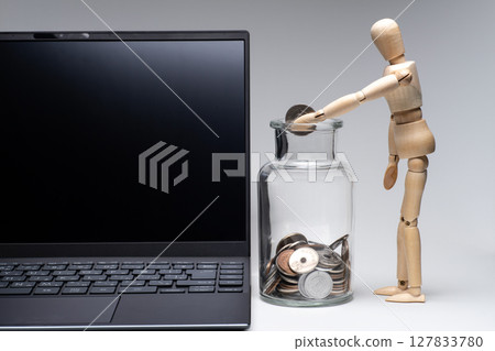 一個畫娃娃用筆記型電腦把錢放進罐子裡 一個畫娃娃用筆記型電腦把錢放進罐子裡 127833780