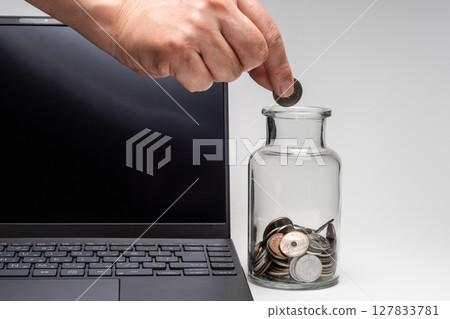 Image of a side job with money in a glass jar next to a computer 127833781