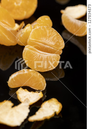 tangerine in a mirror surface, the mirrored black surface and ripe orange tangerines are reflected in the mirror, closeup tangerine in a mirror surface, the mirrored black surface and ripe orange tangerines are reflected in the mirror, closeup 127834873