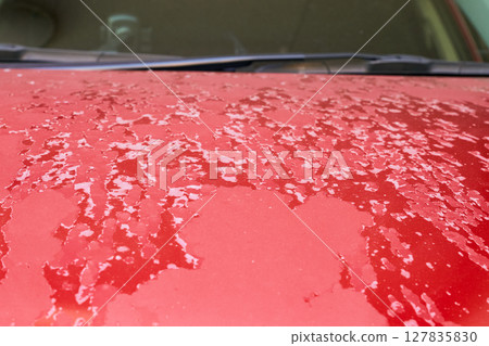 Close-up of a red car hood with peeling paint on the surface due to aging Close-up of a red car hood with peeling paint on the surface due to aging 127835830