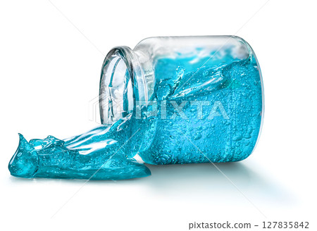 A bright blue hair styling gel spill out of a glass jar isolated on white 127835842