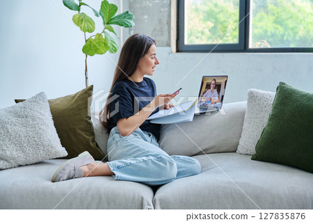 Teenage girl having online therapy sitting at home using laptop for video meeting with counselor 127835876