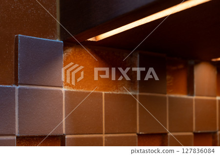 Red ceramic wall tiles with integrated linear lighting under the cabinet. Red ceramic wall tiles with integrated linear lighting under the cabinet. 127836084